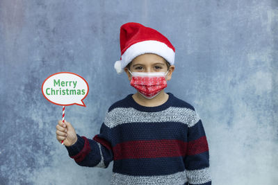 Portrait of boy wearing mask standing against wall