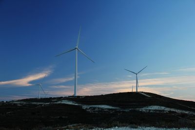 Wind turbines on landscape against sky