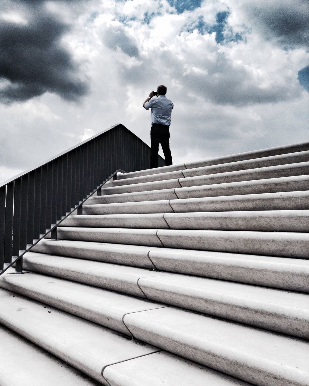 full length, lifestyles, steps, sky, leisure activity, low angle view, casual clothing, railing, steps and staircases, rear view, built structure, cloud - sky, staircase, walking, the way forward, architecture, standing, cloud