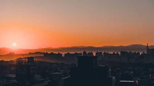 Silhouette buildings against sky during sunset