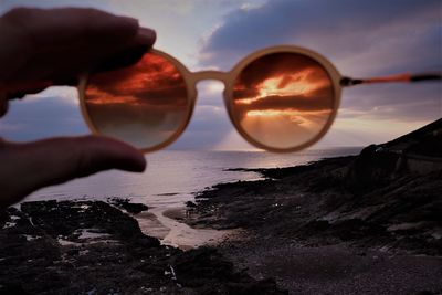 Close-up of hand holding sunglasses on beach