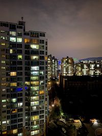 Illuminated buildings in city against sky at night