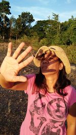 Portrait of woman showing stop gesture while standing on field