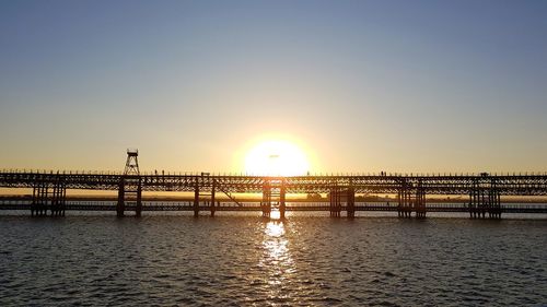 Bridge over sea against clear sky during sunset