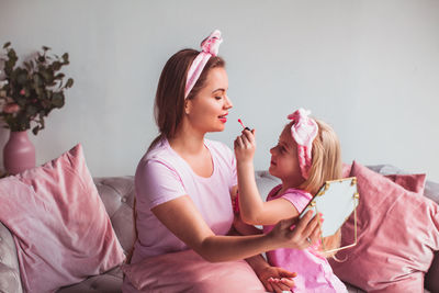 Young woman sitting on bed at home