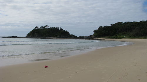 Scenic view of beach against cloudy sky