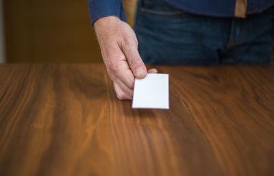 Midsection of person holding paper over table