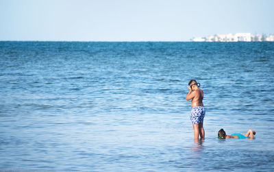 Man standing in sea against clear sky