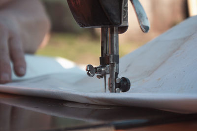 Close-up of person sewing textile on machinery