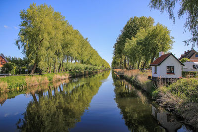 Scenic view of lake amidst trees and houses against sky