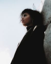 Young woman standing against sky