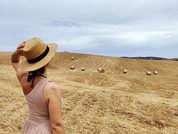 Rear view of woman standing on field against sky