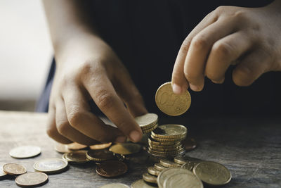 Close-up of hand holding coins over table