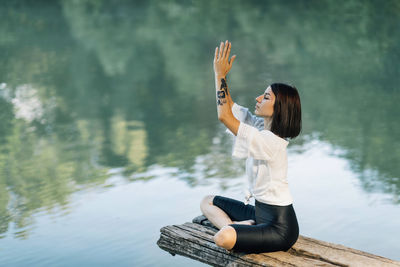 Meditation in nature. woman sitting in lotus position and meditating by the lake