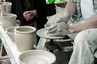 Midsection of man making pots