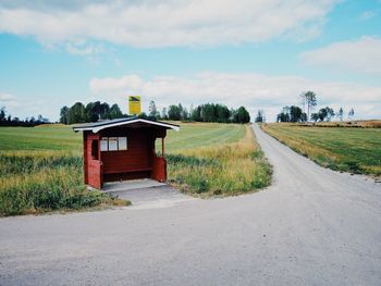 Empty road amidst field against sky