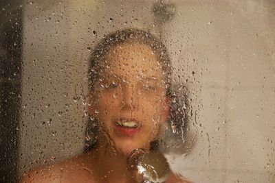 Portrait of woman in wet glass window