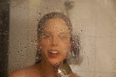 Woman bathing in bathroom seen through window