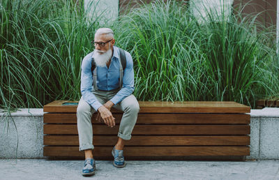 Senior hipster sitting against plants