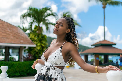 Portrait of attractive young woman standing against sky