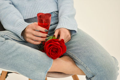 Young girl sitting on a chair holding a red rose in her hand.