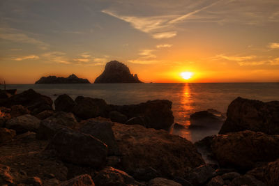 Scenic view of rocks on shore during sunset