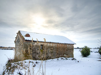 House on snow covered field against sky