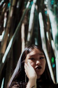 Portrait of serious young woman standing by trees