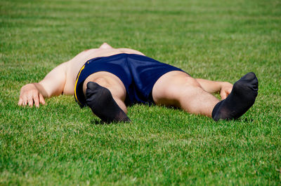 Shirtless man lying on grassy field