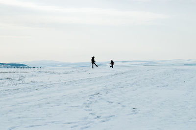 People on snow covered land against sky