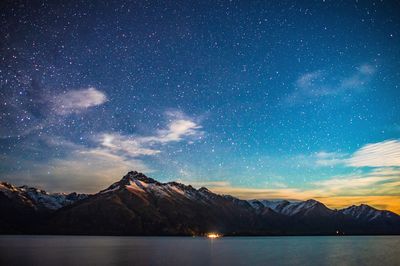 Scenic view of lake and mountains against sky at night