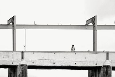 Man standing on bridge against clear sky