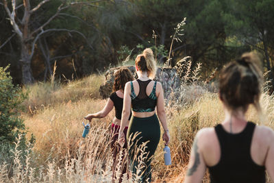 Female friends in sports clothing walking on trail in field during vacation