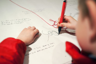 Cropped image of boy writing on paper with pen