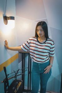 Woman standing against wall at home