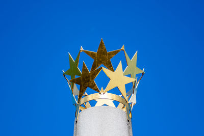 Crown of golden stars on a column with blue sky as a background