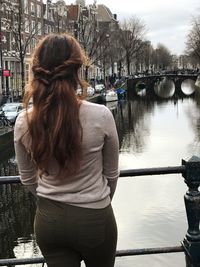Rear view of woman standing by river in city