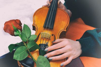 Close-up of woman holding violin with red rose