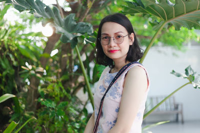 Portrait of young woman standing against plants