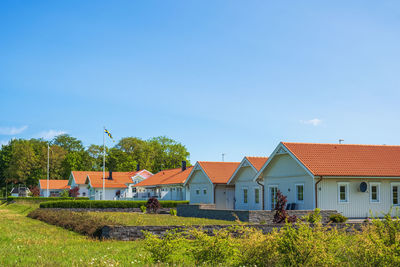Houses on field by buildings against sky