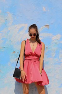 Young woman standing against blue wall