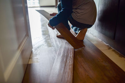 Low section of woman sitting on wooden floor at home