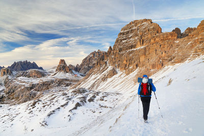 Rear view of woman standing on snowcapped mountain against sky