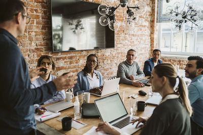 Male entrepreneur discussing about product with business team in board room