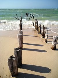 Wooden posts on beach against sky