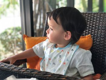 Cute baby boy sitting on chair at home