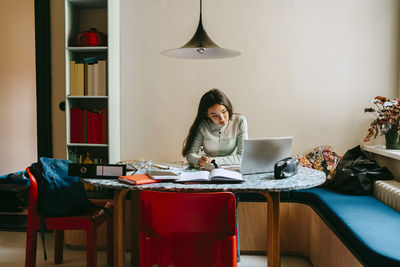 Young woman doing homework with laptop at home