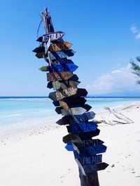Traditional windmill on beach against blue sky