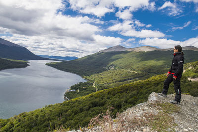 Woman in motorbike clothes is looking over lake in tierra del fuego