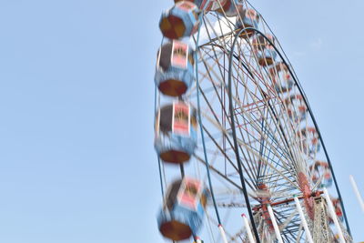 Low angle view of ferris wheel against clear blue sky